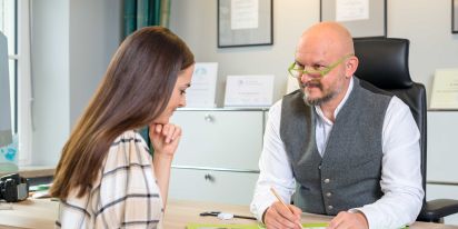Dr. Neumann sitzt mit Patientin am Tisch während eines Beratungsgesprächs