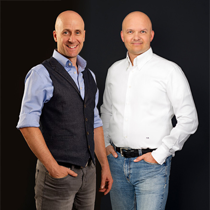 Dr. Thome und Dr. Neumann stehen vor schwarzem Hintergrund
